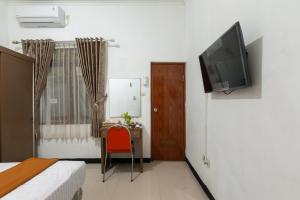 um quarto com uma cama e uma televisão na parede em House of M Bogor Mitra RedDoorz em Bantarkamang