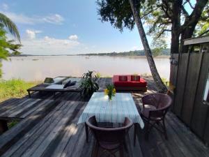 Pomelo Restaurant and Guesthouse- Serene Bliss, Life in the Tranquil Southend of Laos في Ban Khon: سطح خشبي مع طاولة وكراسي بجوار بحيرة