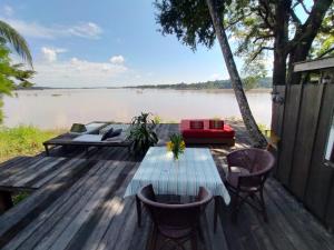 a wooden deck with a table and chairs next to a lake at Pomelo Restaurant and Guesthouse- Serene Bliss, Life in the Tranquil Southend of Laos in Ban Khon