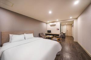 a bedroom with a large white bed and a desk at Anyang ILLOWA Hotel in Anyang