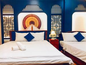 two beds in a room with blue walls and windows at Hue Pink Lotus Hotel in Hue