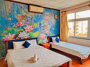 1 dormitorio con 2 camas y un mural de flores en Hue Pink Lotus Hotel en Hue