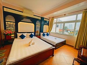 a bedroom with two beds and a large window at Hue Pink Lotus Hotel in Hue