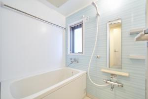 een witte badkamer met een bad en een wastafel bij Luce Takanawa in Tokyo