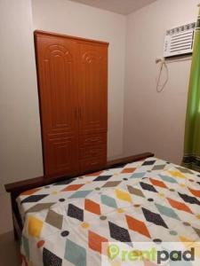 1 dormitorio con 1 cama y armario de madera en Fully Furnished 3 Bedroom House + Public Pool + Wi-Fi + Air conditioning en Mandaue City
