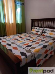 1 dormitorio con 1 cama con un edredón colorido en Fully Furnished 3 Bedroom House + Public Pool + Wi-Fi + Air conditioning en Mandaue City