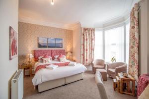 a bedroom with a large bed with a pink headboard at Craignelder Hotel in Stranraer