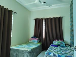 a bedroom with two twin beds and curtains at Teratak Delisha -musslim in Kampong Jemampar
