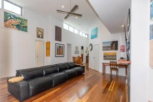 uma sala de estar com um sofá preto e uma ventoinha de tecto em Rakali's View - 7 Wetlands Close em Murray Bridge