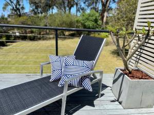 a chair with two pillows sitting next to a potted plant at Sea Breeze on Carroll - 4BR beachside home in Mollymook