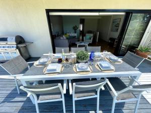 a white table with chairs on a patio with a tableablish at Sea Breeze on Carroll - 4BR beachside home in Mollymook