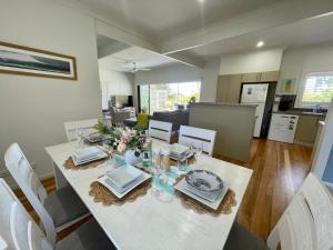 a dining room with a white table and chairs at Sea Breeze on Carroll - 4BR beachside home in Mollymook