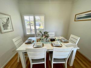 a white dining room table with white chairs and a white table and chairsktop at Sea Breeze on Carroll - 4BR beachside home in Mollymook