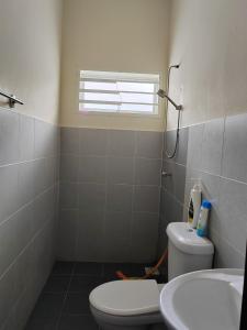 a bathroom with a toilet and a sink and a window at Teratak Delisha -musslim in Kampong Jemampar