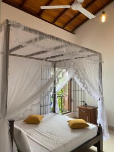 a bedroom with a canopy bed with a window at Villa Lake Mountain in Weligama