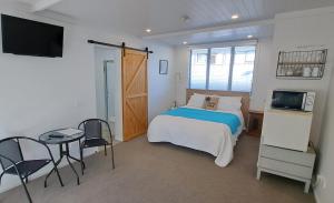 1 dormitorio con cama, mesa y TV en Guest Nest in Whitianga - 2 min walk to Beach, en Whitianga