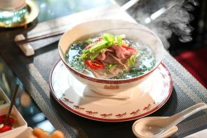 eine Schüssel Suppe auf einem Teller auf einem Tisch in der Unterkunft 9TRIP STAY in Soho Residence - Service Apartment in Ho-Chi-Minh-Stadt