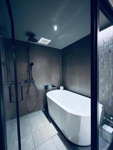 ein Badezimmer mit einer großen weißen Badewanne und einer Dusche in der Unterkunft HOTEL KANMA UENO in Tokio