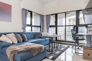 Sofá azul en la sala de estar con ventanas en High Floor New Bldg 4B2bLDK Ximending, Stunning Views • 高層新樓 4房2衛 西門町 美景, en Taipéi
