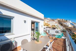 a balcony with a table and chairs and a view of the city at Boutique apartment with BBQ terrace and ocean views in Tabaiba