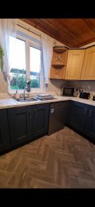 a kitchen with black cabinets and a sink and a window at Roofers Rest in Magherafelt