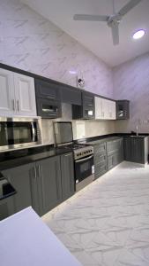 a kitchen with gray cabinets and a white tile floor at دار الضباب dar al dhabab 