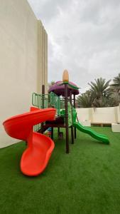 a playground with a slide and a play set on grass at دار الضباب dar al dhabab 