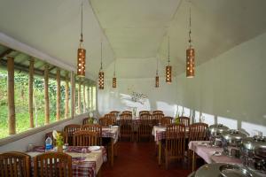 ein Esszimmer mit Tischen und Stühlen und Fenstern in der Unterkunft Blue Bells Resort By Maat Hotels in Munnar