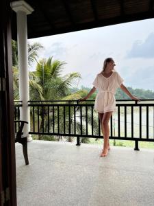 a woman in a white dress standing on a balcony at Villa Lake Mountain in Weligama