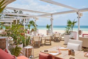 ein Restaurant mit Tischen und Stühlen am Strand in der Unterkunft LUX* Belle Mare Resort & Villas in Belle Mare