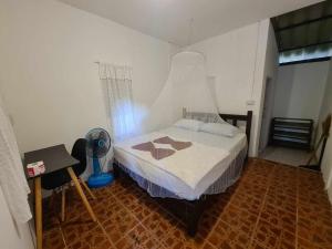 - une chambre avec un lit, une table et un ventilateur dans l'établissement Vijit Bungalow, à Ko Phayam