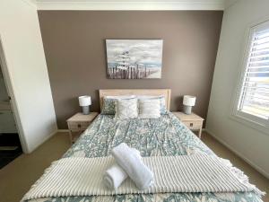 a bedroom with a bed and two night stands at Sea Breeze on Carroll - 4BR beachside home in Mollymook