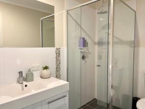 bagno bianco con doccia e lavandino di Sea Breeze On Carroll a Mollymook