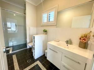 a bathroom with a sink and a shower and a toilet at Sea Breeze on Carroll - 4BR beachside home in Mollymook