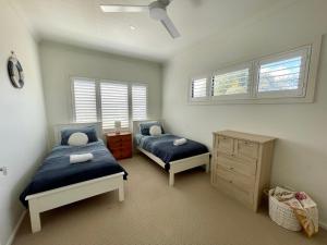 een slaapkamer met 2 bedden, een dressoir en ramen bij Sea Breeze On Carroll in Mollymook