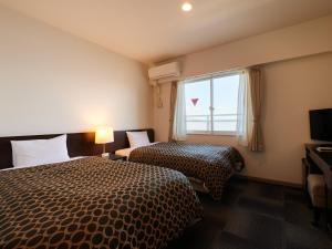 um quarto de hotel com duas camas e uma janela em Wind City Hotel em Tahara
