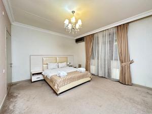 een slaapkamer met een groot bed en een kroonluchter bij Gabala Yeddi Gozel Hotel in Gabala