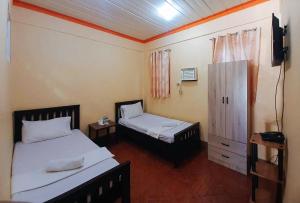 a room with two beds and a television in it at RedDoorz @ Johsons Pension House Butuan City in Butuan