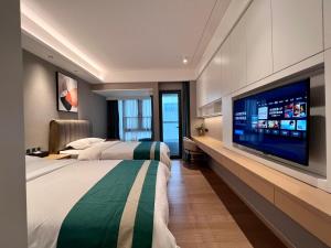 a hotel room with two beds and a flat screen tv at Kaisen Xiyue Hotel Apartment - Shenzhen International Convention and Exhibition Center in Shenzhen