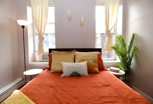 een slaapkamer met een oranje bed en 2 ramen bij Tuk Ahoy - Cozy Condo Apartment in Brooklyn