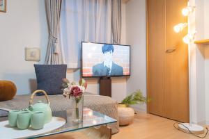 ein Wohnzimmer mit einem Fernseher mit einem Mann auf dem Bildschirm in der Unterkunft 桜の川7 Asakusa 901 Kuramae train 3mins Free WiFi Eight people quiet,cook,perfect facilities in Tokio