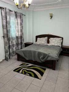 a bedroom with a bed and a rug on the floor at Joel House deido in Douala