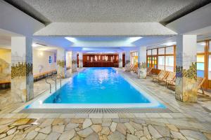 a large swimming pool in a hotel lobby at Hotel Brinje in Zreče