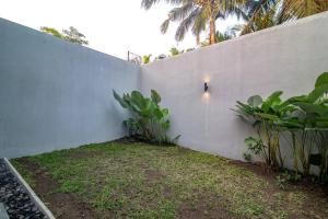 una pared blanca con plantas junto a una valla en Anahata Home, en Tabanan