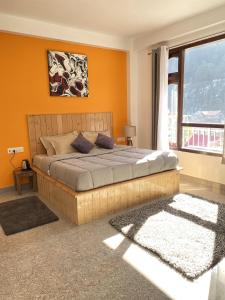 a bedroom with a bed with orange walls and a window at Himtrek Stays, Kasol in Kasol