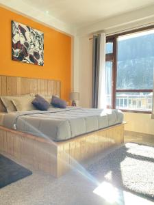 1 dormitorio con 1 cama grande y pared de color naranja en Himtrek Stays, Kasol en Kasol