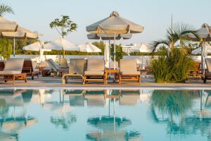 a swimming pool with lounge chairs and umbrellas at Kapetanios Bay Hotel Protaras in Protaras