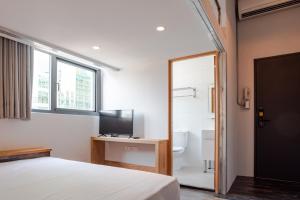 1 dormitorio con cama, TV y baño en miniinn en Taipéi