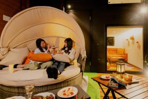 two women sitting on a bed in a room at Mt. Fuji Glamping MOONLIGHT VILLA Kawaguchik in Fujikawaguchiko