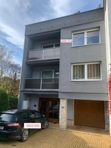 un edificio gris con un coche aparcado delante de él en Apartmán Vsetín Rokytnice, en Vsetín